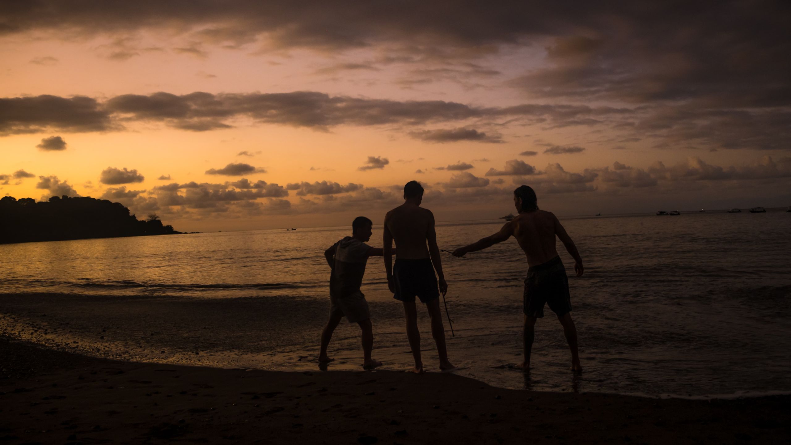 3 persons playing on the beach after sunset.