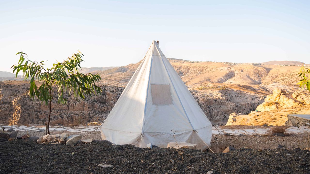 A white tent next to a tree in front of Dana Reserve