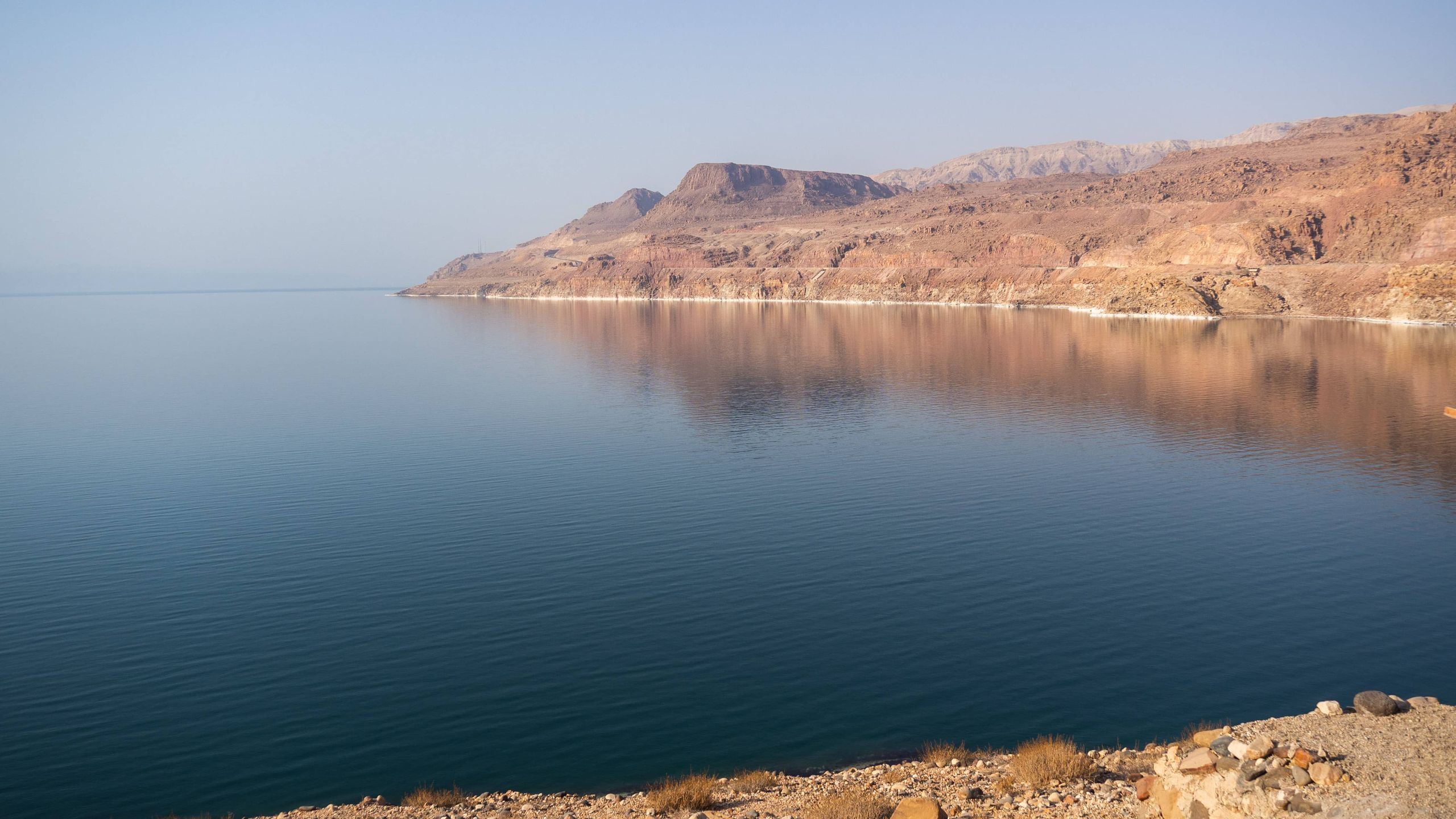 Overview on the blue dead sea with the orange cliffs on the right part