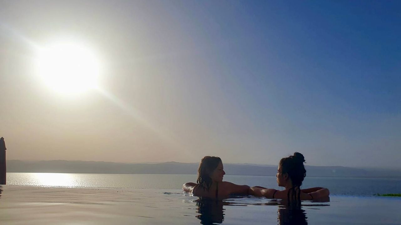 Infinity pool with two persons in the water looking over the dead sea