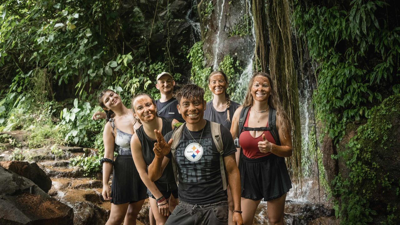 Group of tourists with a guide, wearing mud on their faces