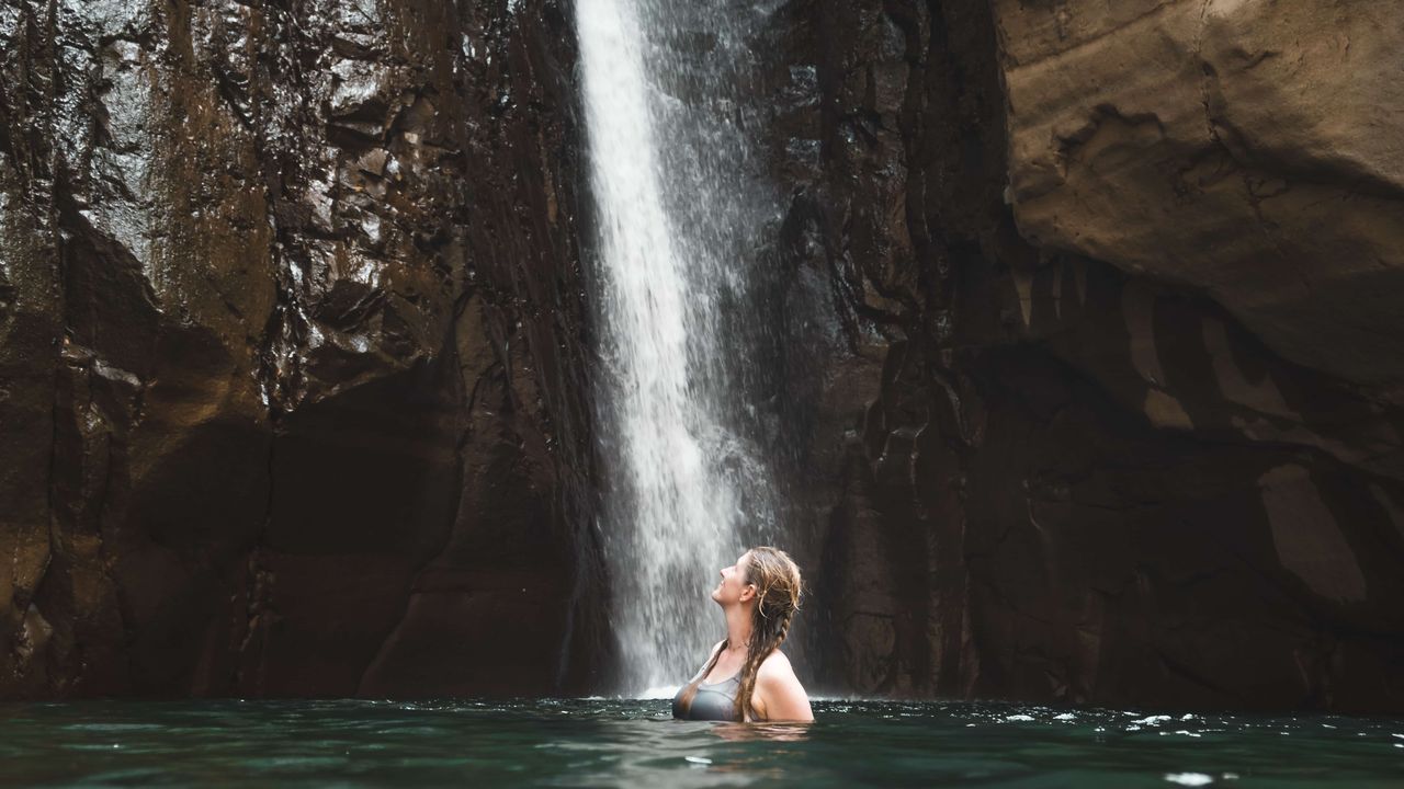 woman looking up to a waterfall