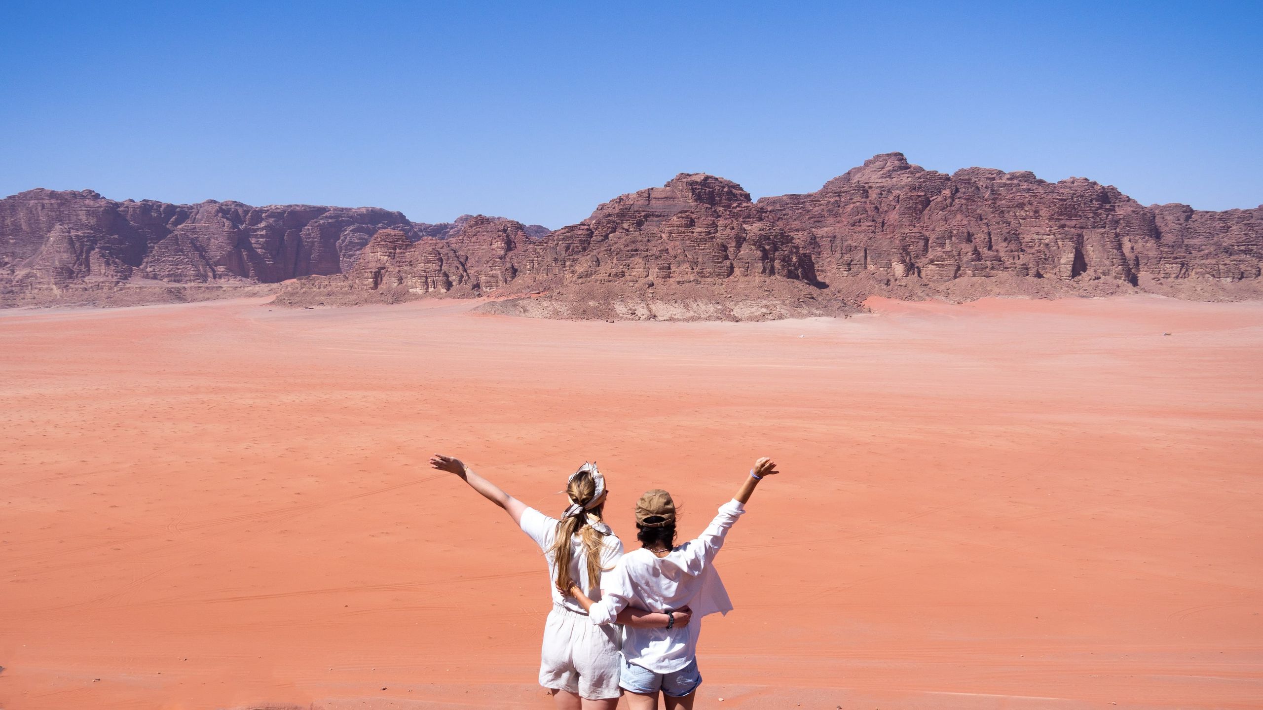 Two persons standing in front of the Wadi Rum desert