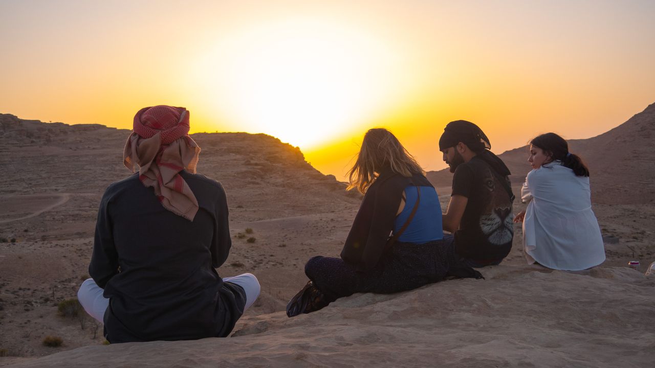 Four people watching the sunset in the sand dunes of the desert